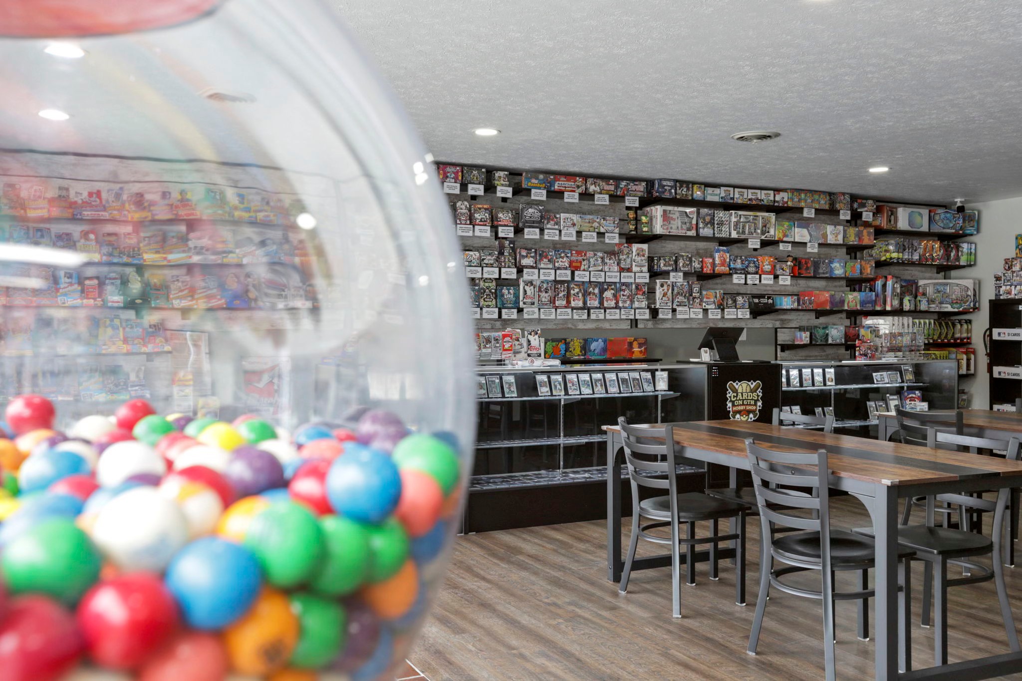 Cards on 6th Hobby Shop interior located in Lancaster Ohio in Fairfield County, game machine with Pokémon prizes, featuring a gumball machine